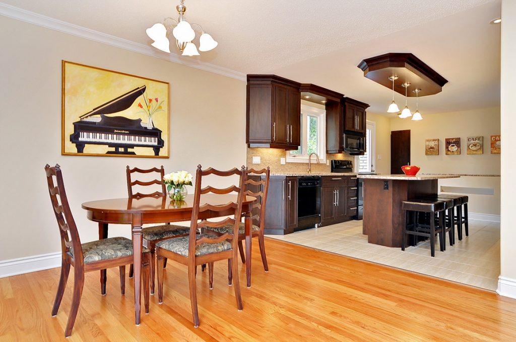 A three-quarters view of a renovated kitchen and dining room, with beautiful hardwood floors.