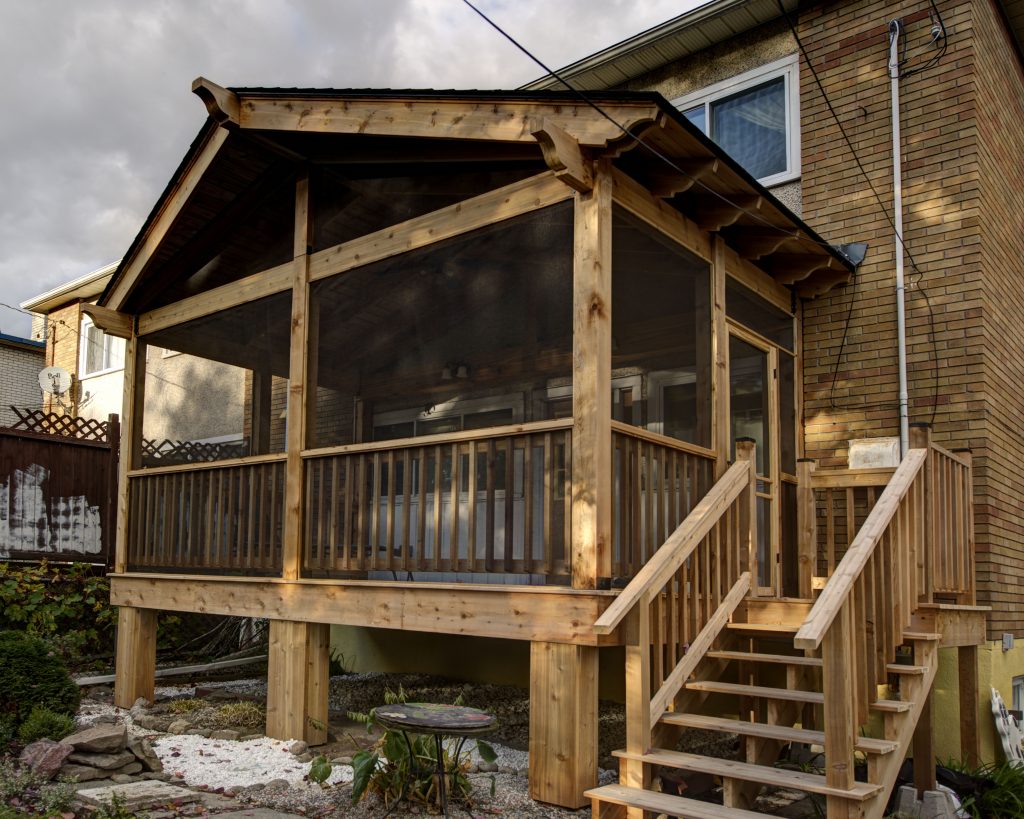 A screened-in backyard patio and deck, attached to a stylish modern home.