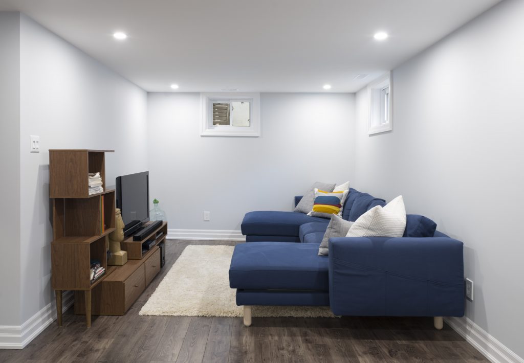 A cozy home theatre space, with a modest TV and comfortable couch, are a welcome addition to this basement renovation.