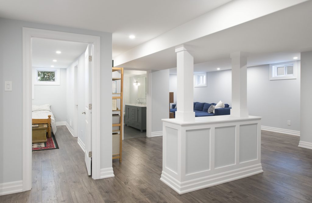 A view of a finished basement, giving a glimpse of a rec room, bathroom, and additional storage.