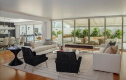 A beautifully renovated, open-concept home living room sits in front of a wall of glass windows looking out onto a stunning patio.