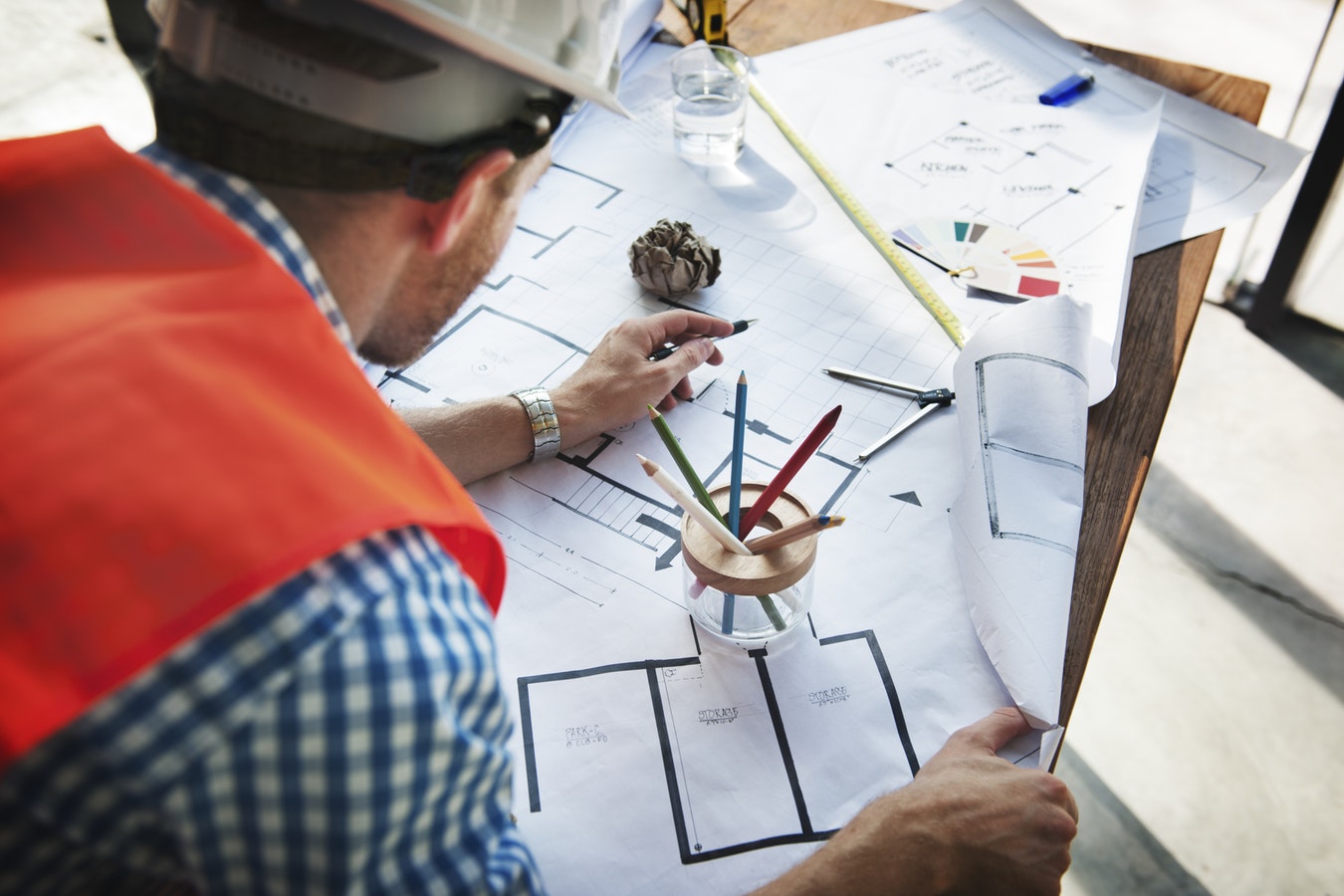 A contractor leans over a set of custom home blueprints with a pen in hand.