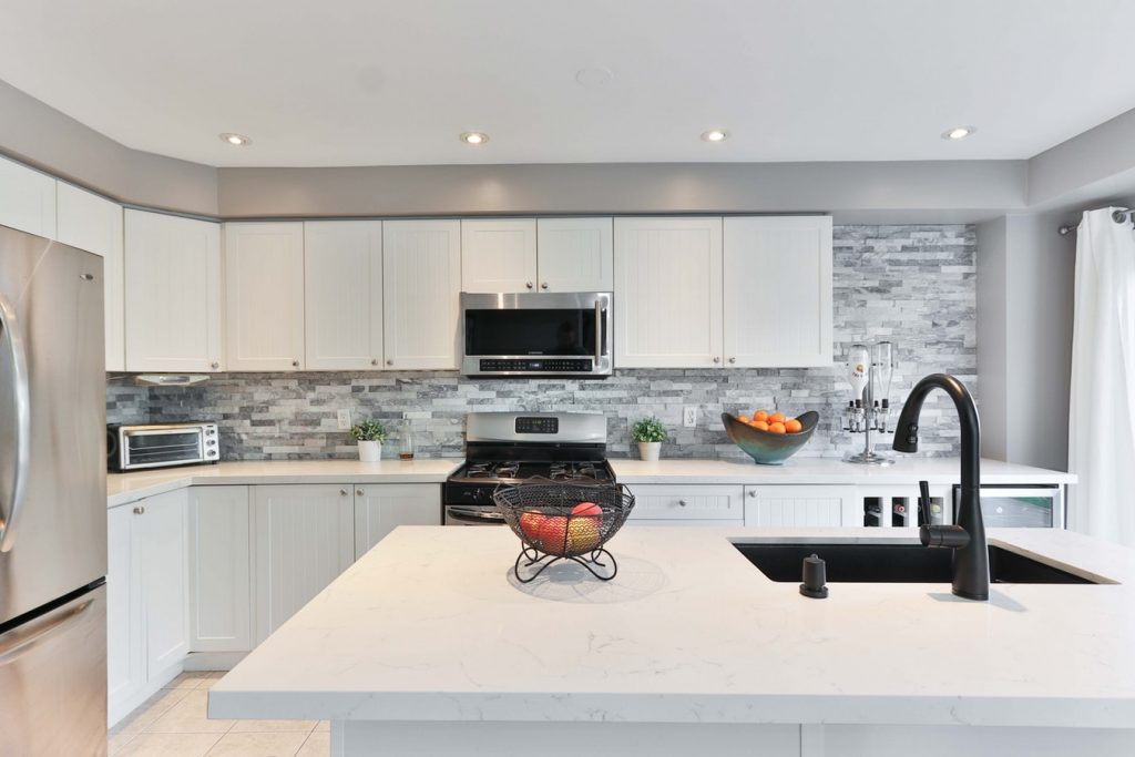 A contemporary kitchen design that incorporates the microwave into the range hood above the stove.