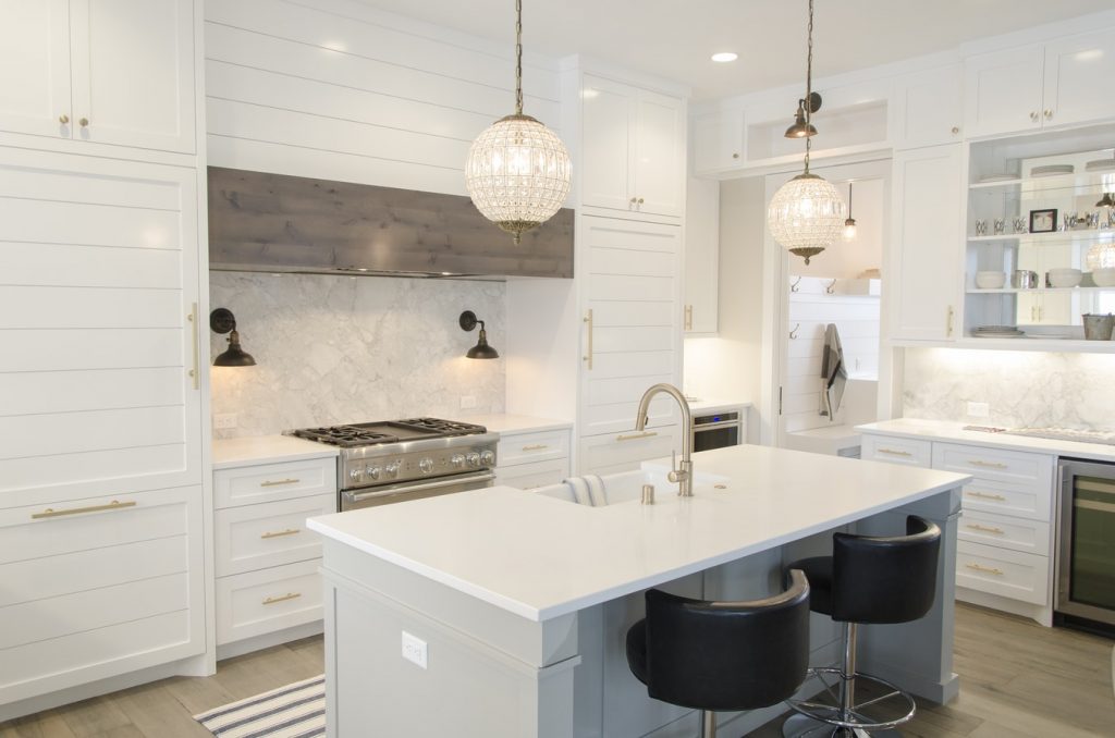 A stylish, white-and-gold modern kitchen with an island and bar seating.