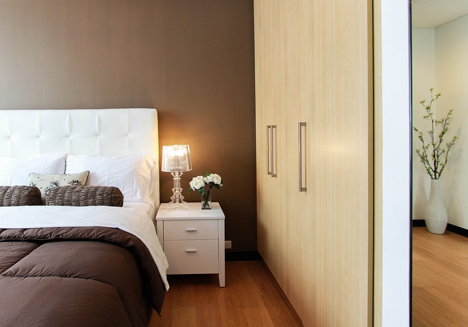 A large closet and mirror face onto a bed in a modern bedroom.