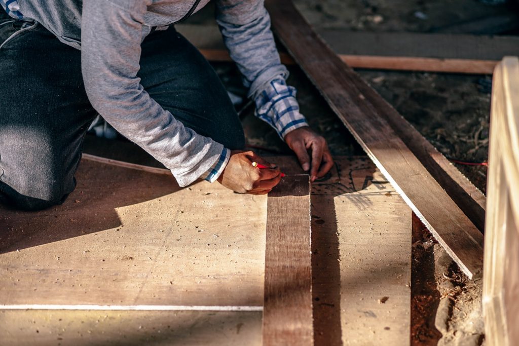 A contractor measures plywood in a custom home build.