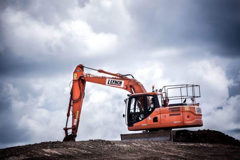 An excavator sits on an earth-covered field.