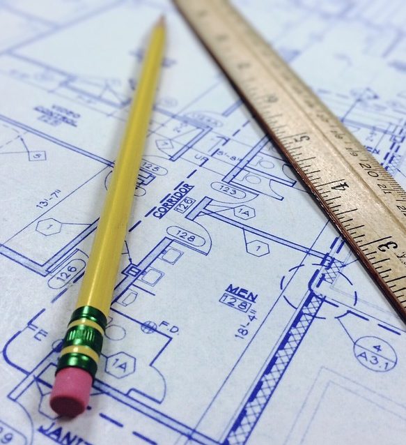 A pencil and ruler sit on top of a set of blueprints.