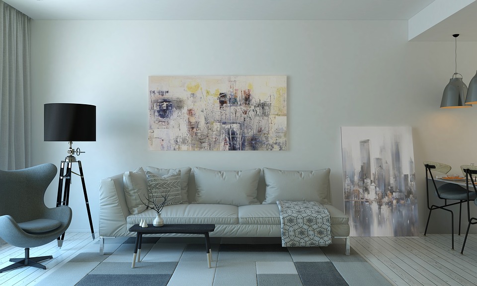 A contemporary living room with a modern couch and chair, as well as abstract paintings.