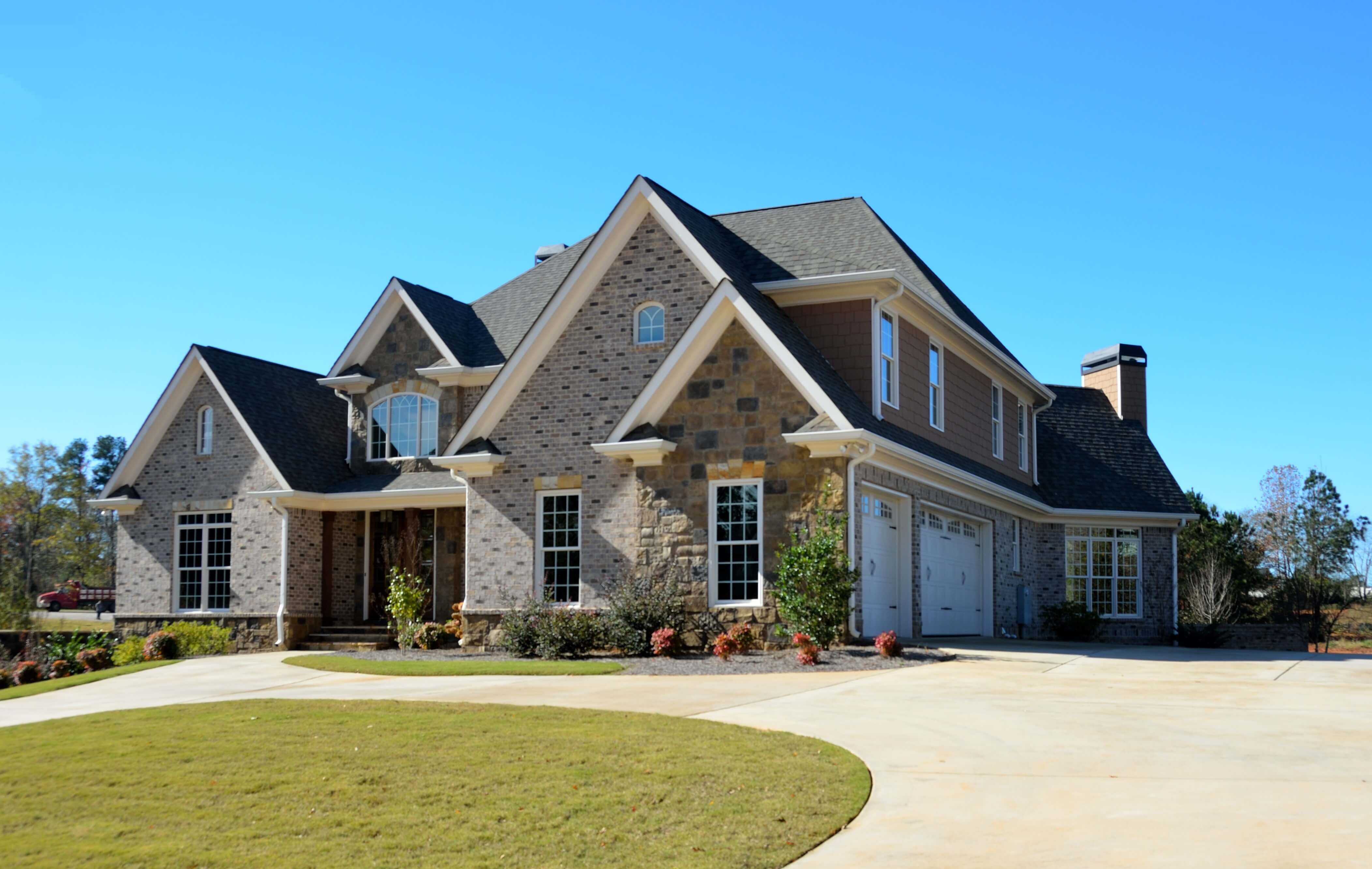 Beautiful custom home on top of a gentle rise, featuring large vaulted roofs and big windows.